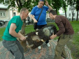 Памятник "Ежику в тумане" поставили в Киеве, на улице Золотоворотской угол Рейтарской. Авторы памятника - столичные умельцы Владимир Колинько и Георгий Куровский, которые уже несколько лет облагораживают уродливые пеньки в городе, вырезая причудливых рыб, котиков, Буратино, балерину и множество других творений. Основой памятника стал ствол испортившегося дерева. Была использована довольно интересная техника при выполнении иголок ежика: пень обвязали металлической сеткой, а в ней закрепили шурупы. Многие туристы оставляют монетки в сетке, что это символизирует неизвестно, но, скорее всего, такой жест означает желание встретиться с Ежиком еще раз.
Вот фотография, на которой показана установка скульптуры.