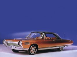 В 1963 году "Chrysler" стал первым в мире автопроизводителем, запустившим газотурбинные автомобили в серийное производство. Chrysler Corp. развернула уникальную программу под лозунгом «dream car в жизнь». Впервые в истории начался (мелко)серийный выпуск «автомобиля мечты» под говорящим названием Chrysler Turbine: легковушка с газотурбинным двигателем. Не только (и не столько) для выставок и демонстраций, сколько для повседневной эксплуатации. По замыслу, экспериментальная модель строилась в 55 экземплярах, из которых полсотни предназначались к раздаче в пользование американским автомобилистам по всей стране.
Как выбирали счастливых участников масштабного эксперимента — отдельный разговор. Так или иначе в октябре 1963 м-р Lynn A.Townsend, тогдашний президент Chrysler Corp., лично вручил ключи от новенького Chrysler Turbine первым пользователям – рядовой семье из чикагского пригорода. Процесс пошел. По программе, каждый из участников эксплуатировал машину в течение трех месяцев, а затем передавал ее очередному. Всего в эксперимент вовлекались две сотни автомобилистов. В Chrysler Corp. рассчитывали получить неоценимые сведения об эксплуатационных качествах «турбинной» легковушки – в условиях, приближенных к боевым. А также проверить реакцию потенциальных покупателей на непривычное транспортное средство – и оценить его рыночный потенциал.
Прогрессивная турбина вместо безнадежно устаревшего д.в.с. – вот ведущая идея крайслеровского dream car образца 1963. И в самом деле под капотом размещался газотурбинный двигатель (уже IV поколения) с вращающимися регенераторами тепла отработанных газов. Их температура на выхлопе падала до каких-то 245о C, — то есть, тепловая энергия утилизировалась довольно глубоко. Компактный агрегат весил 185+ кг и стыковался с 3-скоростным «автоматом» TorqueFlite (без гидротрансформатора, надобность в котором отпала в силу 2-вальной конструкции турбины).
Объявленная максимальная мощность агрегата (SAE «нетто») – 130 л.с. при 3600 оборотах выходного вала. То есть, сама-то вторичная (тяговая) турбина крутилась при максимальной мощности на 44600 мин-1, однако обороты понижались встроенным понижающим редуктором – до обычного в легковом автомобилестроении уровня («отсечка» на 4680 мин-1). Не сказать, что турбина отличалась выдающейся мощностью (тогда уже делали литражные «восьмерки» и на 400 сил – «брутто»). Зато крутящий момент она выдавала (на выходном валу) очень неслабый — за 575 Нм. Причем прямо от 0 оборотов, так что на разгонную динамику Chrysler Turbine никто не жаловался.
Мощная тяга транслировалась на неразрезный ведущий мост, подвешенный на продольных листовых рессорах. Передняя подвеска – на двойных поперечных рычагах, стандартная для американской легковушки тех лет ходовая. Узенькие (по нынешним понятиям) покрышки с диагональным кордом – и барабанные тормоза «по кругу». Рулевой механизм «винт-шариковая гайка» с гидроусилителем – все как у всех в начале 60-х. Так что Chrysler Turbine представлял собой пеструю мозаику передовых и традиционных (а где-то даже устаревших) технических решений, осторожное продвижение.
Как обычно для газовых турбин, крайслеровский агрегат оказался по-настоящему многотопливным: он успешно работал на неэтилированном бензине и авиационном керосине. И даже на растительном масле, хотя участникам эксперимента рекомендовали стандартное дизтопливо. Газотурбинный агрегат работал исключительно надежно и не доставлял добровольцам особенных хлопот.
Программа благополучно завершилась в начале 1965, после чего полсотни «турбинных» легковушек отправили на слом. В течении трех лет на этих автомобилях поездило около 200 человек, преимущественно проверенных клиентов фирмы, которые и вынесли неутешительный вердикт. Да, экзотичный мотор "Chrysler Turbine Car" превосходен по характеристикам. Он настолько тяговит и высокооборотен, что нет нужды в КПП — двигатель вращает ведущие колеса напрямую. Увы, но газовая турбина свистит как Соловей-разбойник, что невыносимо в дальних поездках. Второй недостаток — непомерный расход топлива, составлявший порядка 24 л /100 км. Чудовищный аппетит для относительно небольшой машины. В итоге программу газотурбинных автомобилей закрыли.