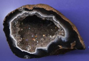 Камень "с блестючками" - скорее всего жеода мелких кристаллов, скорее всего халцедона, а вот что конкретно - это нужно смотреть воочию, специалисту. Спил ровный, потому что его так спилили для получения поделочного материала - само по себе в природе так не получается.