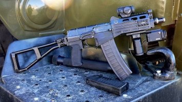 Есть и другие интересные вещи. Только широкого применения они не нашли...

Возможность скрытой переноски оружия для спецподразделений очень важна. Поэтому появляются специальные разработки, из-начально ориентированные на скрытую переноску. К такому типу оружия относится СР-3 "Вихрь".

Автомат был разработан в начале 1990-хх годов в ЦНИИ Точного Машиностроения (г. Климовск). Работы по созданию нового автомата и совершенствованию конструкции велись до 1994 года. Наибольшую роль в его создании сыграли конструкторы Борисов, Левченко, Тышлыков. В 1996 году после ряда испытаний автомат был поставлен на серийное производство.

Базой этого автомата явился специальный автомат ВАЛ. В отличие от прототипа, в "Вихре" нет интегрированного глушителя. Автомат имеет весьма небольшие размеры, сравнимые с размерами пистолетов-пулеметов, однако заметно превосходит их по огневой мощи за счет использования специальных бронебойных патронов СП-6 калибра 9мм (9х39мм). Тяжелая дозвуковая пуля имеет большую проникающую способность. На 100 метрах пуля пробивает две титановые пластины 1,4 мм и 30 слоев кевлара. Благодаря этим патронам СР-3 позволяет успешно бороться с противником в индивидуальных средствах зажиты - бронежилетах (вплоть до 3 класса защиты по ГОСТ).

Длина со сложенным прикладом всего 360 мм, с откинутым прикладом 610 мм, масса всего 2 кг. Вихрь имеет складной приклад, оснащен компенсатором-пламегасителем. Емкость магазинов 10-20 патронов. Небольшие размеры и "обтекаемая" форма позволяют носить оружие скрытно, под верхней одеждой, и применять в стесненных условиях, например из салона автомобиля или в толпе. Для уменьшения габаритов рукоятка взведения перенесена в переднюю часть оружия и выглядит как небольшая клавиша. Приклад склады-вается наверх и практически не выпирает за контуры ствольной коробки. В первых образцах приклад открывался автоматически, при нажатии на специальную кнопку, но потом от этого отказались, причем не совсем обоснованно. Изменена конструкция предохранителя - теперь он легко переключается одним нажатием большого пальца.

Автоматика работает за счет отвода газов из канала ствола к поршню затворной рамы. Запирание затвора происходит на пять бое-вых выступов. Ударно спусковой механизм позволяет вести одиночный и полностью автоматический огонь, стрельбы фиксированными очередями не предусмотрено. Предохранитель и переводчик выполнены раздельно. Переводчик огня кнопочного типа расположен за спусковым крючком. Предохранитель двусторонний, расположен на ствольной коробке. Прицельные приспособления включают в себя мушку в передней части оружия и перекидной двухпозиционный целик на крышке ствольной коробки.

Автомат может вести огонь как автоматически, так и одиночным огнем. Дальность эффективного поражения до 200 метров. По эффективности поражения и мощности боеприпаса на дистанции до 200 метров оружие вполне конкурентоспособно со штурмовыми винтовками. Кроме того наличие укороченного десятизарядного магазина делает "Вихрь" особенно удобным для скрытого ношения и внезапного применения. Кроме достоинств у "Вихря" есть и один недостаток - оружие дорогое и достаточно редкое.

Тактико-технические характеристики

Калибр: 9 мм
Применяемый патрон: 9х39
Прицельная дальность стрельбы: 200 м
Темп стрельбы: 900 выстр./мин.
Ёмкость магазина: 10 или 20 патронов
Начальная скорость пули: 270 м/с
Длина со сложенным прикладом: 360 мм
Длина с разложенным прикладом: 610 мм
Высота с магазином на 10 патронов: 160 мм
Ширина: 40 мм
Масса с пустым магазином: 2 кг
Масса со снаряженным магазином на 10 патронов: 2,1 кг