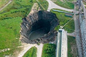 Дырка не от взрыва, это обвалившаяся кровля лавовой трубки. По краю не лунки, а куски породы, тёмные в инфракрасном спектре или тени от них. Это не осыпь, а пологий склон внутрь, к провалу.