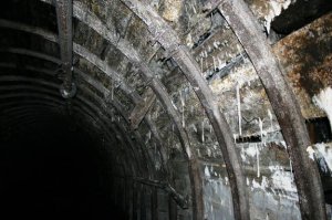 "Затяжка" - между секциями арочной крепи, обычно доска или обапол, на капитальных выработках - железобетон.
"Коногонка" - от "коня гнать".
Рубили, я так понял, обычным молотком, а не отбойным, а кислород выгорит только в районе скопления метана, который собирается вверху, как более лёгкий газ. И опять-таки криво написано, где он загорелся, в откаточном штреке - не может, ибо проветриванием выдувает, в лаве - только вверху, а в вентиляционном штреке бригаде на 6 человек просто делать нехер.