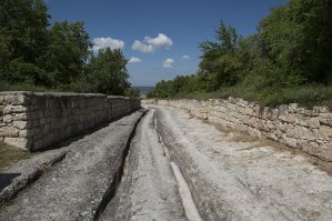 "Таинственные колеи из бронзового века" - ничего таинственного в них нет. Насчет "вертикальных" автор естественно приврал, а так это обычные колеи от повозок. Встречаются во многих древних городах.
Пример - Чуфут-Кале, Крым