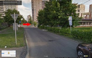 Судя по координатам, это Железнодорожный, Московская область. И если покрутить панараму, то становится видно что эта дорога находится внутри жилой зоны, въезд в которую с октябрьской улицы обозначен специальным знаком 5.21, на фото стрелкой указан поворот на часть пути по которому ехал автор.

И согласно пункту ПДД 17.1: "В жилой зоне, то есть на территории, въезды на которую и выезды с которой обозначены знаками 5.21 и 5.22, движение пешеходов разрешается как по тротуарам, так и по проезжей части. В жилой зоне пешеходы имеют преимущество, однако они не должны создавать необоснованные помехи для движения транспортных средств."

Т.е. женщина согласно приоритету двигалась по проезжей части, и сознательно или специально помех регу не создавала. 
Пешеходные переходы внутри жилых зон, создаются с целью усиления внимательности водителя при проезде конкретных участков жилых зон.