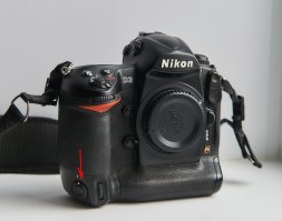 У профессиональных камер по умолчанию две спусковые кнопки - вторая как раз для съёмки вертикальных кадров. А к модели, которую вы привели в пример, и всем другим зеркальным фотокамерам, снизу можно прикрутить батарейную ручку, на которой тоже находится вторая спусковая кнопка. Так что прежде чем писать, стоило бы изучить матчасть.