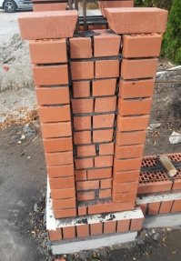 Зря на каменщиков гонишь!
Угловой кирпич лежит ровно.
Швы между кирпичами будут облагорожены расшивкой, скорее всего цветной
А  нишу посередине специально оставили для декоративного камня и как раз под него чем кривее лежит основание, тем лучше приклеиться.

Так что АФТОР , не зная брода , не лезь в воду.
Каменьщики ему видите-ли не красивые, а ты пойди найди красивых :)