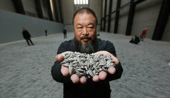 Надо бы рассказать кто такой Ай Вэйвэй, и почему семена подсолнечника.
«Семена подсолнечника» (англ. Sunflower seeds) — инсталляция знаменитого современного китайского художника Ай Вэйвэй (1957 г.) впервые открывшаяся в 2010 г. в Турбинном зале Лондонской галереи современного искусства Тейт Модерн. Проект представлен в виде более 100 млн фарфоровых семян подсолнечника усыпанных по всей площади самого большого зала музея.
Фарфоровые семена подсолнечника, сделанные вручную 10 см слоем покрывают площадь в 1000 кв. м. 100 миллионов семян весят около 150 тонн. Каждое семя выполнено из чистого фарфора вручную. Ни одно из семян не похоже на другое. Каждый элемент был сделан и раскрашен индивидуально. Над экспозицией работали свыше полутора тысяч китайских рабочих в течение 2,5 лет, и все это время информация о проекте не разглашалась. Изначально Ай Вэйвэй решил сделать только 3 млн семян, но после понял, что этого будет недостаточно для полного завершения экспозиции, и работы продолжились. В итоге количество семян превышает население Пекина в пять раз.

При изготовление семян использовались традиционные методы работы с фарфором. Это придает еще больше уникальности инсталляции. Все мастера, все 1600 человек были из города Цзиндэчжэнь (Jingdezhen景德镇), также известного как «столица императорского фарфора».

Как говорит Ай Вэйвэй, чтобы понять Китай с его историей, мало прочитать это в книгах, надо увидеть все вживую, иметь возможность «дотронуться» до истории, поэтому в первые дни представления инсталляции не была огорожена. Зрители могли пройтись по этому «безмерному, серому морю». По усыпанному семенами, полу можно было ходить, лежать, играть, перебирать семена, люди могли делать с ними все, что угодно. Также Ай Вэйвэй был не против, того, что некоторые поддавались соблазну и забирали с собой на память пару семян. Но вскоре, после открытия выставки «хождение по фарфору» было запрещено: это создавало много фарфоровой пыли, опасной для здоровья. Экспозиция была оцеплена, но это не мешало людям проникнуться работой художника.
Искусство Ай Вэйвэя формально часто опирается на утопические амбиции «нового мира» конструктивизма. При этом, художник создает достаточно тонкие политические произведения, которые занимают критическую позицию в отношении радикальных изменений, происходящих в Китае.

Семена были мощным символом Культурной Революции (1966—1976). Китайский концептуальный художник Ай Вэйвэй ассоциирует миллионы семян подсолнечника с китайским народом. Во времена Культурной Революции правителя Мао Цзэдуна изображали на плакатах в виде солнца, а жителей страны в виде подсолнечников, тянувшихся к нему. Фарфоровые семена Ай Вейвея символизируют миллионов жителей Китая, похожих внешне, но разных внутри. Инсталляция крошечных семечек ставит перед посетителями вопрос о роли индивидуума в современном обществе. Также мастер показывает пример нетрадиционного использования традиционного китайского материала, исторически занимавшего львиную долю всего экспорта страны. Он считает, что фарфор мог бы найти еще много применений в нашей жизни, и учит нас мыслить масштабно и креативно.