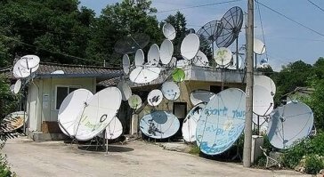 Оптика, говорите?! И где вы столько оптики видели, особенно на дереве? Попытаюсь обьяснить этот кошмар электрика или связиста. Я сделал скрин побольше, чтоб понятнее было, и подписал номерами. Номер 1 - изолятор, крепится на столбе и на доме, откуда потом идет разводка в внутри дома (данный способ неактуален, в деревнях еще встречается). 2 -  кабель (на фото видно, что он в легкой оплетки и тяжелый, 4-жильный, обычно такой кабель поключают к к ларьку, столовой, с металическим троссиком, чтобы провод не провисал, 5 - разтяжка, механизм, который затягивает тот самый троссик,  и недает провиснуть кабелю. 3 - похож на обыкновенный сплиттер, который используется в спутниковом ТВ,  к нему подключают,  в зависимости от расположения спутников, головки тарелок, а дальше на рессивер. Не-е, может здесь и есть оптика, просто это очень дорого!!!Больше это напоминает вот это!!!
