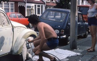 Мужик в сланцах красит тачку, а рядом его жена сушит белый платок. В принципе стиль одежды соответствует поступкам