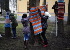Украшение деревьев вязаной одеждой   одно из популярных направлений уличного искусства. Родоначальницей  вязанного стрит-арта  (его же называют yarnbombing   взрыв пряжи) стала Магда Сэйег (Magda Sayeg), владелица магазина одежды из Америки. В 2005 году Магда, поддавшись творческому порыву, связала чехол для дверной ручки, но даже и предположить не могла, какой восторг ее поступок вызовет у людей. Именно тогда у Магды зародилась мысль всерьез заняться вязанием  одежды  для украшения тех или иных уличных объектов. Главной особенностью ярнбомбинга является использование ярких цветов пряжи   таким образом мрачные предметы городской инфраструктуры превращаются в детали, которые привлекают внимание каждого прохожего. Такое искусство, считают его сторонники, уменьшает количество депрессий и поднимает настроение у людей. Вязаный стрит-арт приобрел огромную популярность и распространился по США и Европе, а в 2011 году пришел и в Россию.