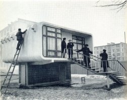 Идея не нова.
В 1961 году в Ленинграде был произведен уникальный строительный эксперимент: на Торжковской улице в глубине квартала между домом 24 корпус 1 и 24 корпус 2 был построен небольшой особняк. Уникальность его заключалась не в ярком архитектурном облике, не в том, что среди типовых хрущевских пятиэтажек вдруг возник одноквартирный особнячок, а в том, что сделан он был из  пластмассы. 
По сути, домик был двухэтажным. Нижний этаж был техническим, где находились различные коммуникации и установка воздушного отопления и вентиляции. Стены технического этажа были выполнены в виде железобетонного каркаса, заполненного стеклоблоками. Пластмассовым являлся верхний (жилой) этаж, приподнятый на 2 метра 20 сантиметров над уровнем земли.
Авторами экспериментального дома из пластмасс были архитектор А.П. Щербенок и инженер Л.Г. Левинский. тены дома монтировались из панелей, которые делались из двух слоёв прочного стеклопласта с заключенным между ними слоем пенополистерола (игравшего роль утеплителя). Максимальная толщина стен достигала 14 сантиметров, жесткость им придавали своеобразные скорлупные конструкции. Инженеры-экспериментаторы тогда подсчитали, что теплозащитные свойства таких пластмассовых  сэндвичей  будут равны двухметровой кирпичной стене.
В пластмассовом доме запроектировали однокомнатную квартиру с кухней, совмещенным санузлом, кладовкой и небольшой террасой. Авторы эксперимента придумали максимальное количество элементов из пластмасс: огромные окна были выполнены из оргстекла, трубы из винипласта, обои из полихлорвиниловой пленки на бумажной основе.
В этом маленьком домике никто не жил. Основной целью эксперимента была проверка возможностей изготовления различных строительных изделий из пластмасс, а также изучение эксплуатационных показателей пластмассовых зданий.
По результатам анализа и обобщения трехлетних наблюдений над первым отечественным, полностью пластмассовым домом с середины 60-х годов перешли к практическому внедрению пластмасс в строительство. В Москве в 4-м Вятском переулке была построена пластмассовая пятиэтажка.
Необходимо отметить, что советский пластмассовый дом не был единственным в мире. В 1957 году пластиковый  Дом будущего  построили в Диснейленде. В 1963 году Дитер Шмидт построил свой пластмассовый дом, конструктивно схожий с ленинградским собратом.
В 1969 году в Германии возвели ещё один пластмассовый особняк, превосходивший по размерам своих предшественников.