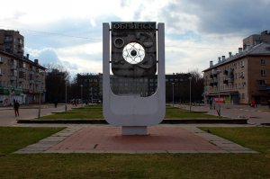 Корабль давно убрали (демонтаж начинался в 2012 году). В стеллу пару лет назад вернули ядро атома. На стелле видны изображения 4-х стихий Обнинска: медицина (МРНЦ РАМН (именно сюда едут лечить раковые опухоли) родоначальник ряда направления в лучевой терапии и всегда был ведущим центром в лечении рака, также именно здесь разработаны арбидол, кагоцел и многие другие препараты; метеорология (ВНИИГМИ МЦД, самая высокая исследовательская (метеорологическая) мачта в мире); атомная промышленность (первая в мире АЭС, ГНЦ РФ-ФЭИ является родоначальником быстрых реакторов) и химия(НИИФХИ им. Карпова("кремлёвские таблетки" делали здесь)). Мост давно превратили из подвесного в мост на опорах. Обнинск всегда называли "город в лесу или лес в городе", потому что было много зелени, к сожалению сейчас очень много застраивается. За последние годы территория Обнинска увеличилась в 1,5-2 раза, т.к. сильно сместили границу. В Обнинске единственный в Калужской области бассейн соответствующий олимпийским нормам (50 м). В Обнинск из Москвы перебирается народу больше чем в обратном направлении. Жильё самое дорогое в области. Самый первый реактор был совсем не в Обнинске: первый в мире - Чикаго (СР-1); первый в Европе - Москва (Ф-1). Несколько фотографий вообще не из Обнинска, а из ближайших посёлков и СНТ. Раз уж была фотография с кораблём, которого уже нет, то добавлю старое фото где не только корабля, но и крепость и лодочки в этом дворе