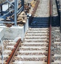 Ну, не знаю что конкретно происходит на этой картинке. Однако подобное видела много раз - в морском порту. Там большие погрузочные краны двигаются по причалу вот на таких рельсах. Но через какое-то кол-во метров на рельсах сделаны точно такие бетонные подушки (они же опоры под какой-нибудь светильник). Как мне тогда сказали, это необходимо, чтобы кран мог перемещаться на заданное расстояние, но ни при каких обстоятельствах не мог двинуться дальше  по причалу - чтобы не было навала на другой кран или на пароход. А большие брустверы, как на ж/д ветке, делать бессмысленно, не та нагрузка. 
Поправьте, кто в теме.