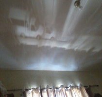 Здесь не случайная игра теней! Ну улице действительно стоит автомобиль (возможно, один) и через отверстия в шторе картинка проецируется на потолок.
Как в Камере Обскура.