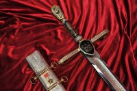 Меч Победы



 Меч Победы  представляет собой образец авторского, художественно украшенного, длинноклинкового оружия, покрыт золотом высшей 999,9 пробы. Особую парадность изделию придает инкрустация полудрагоценными уральскими камнями: гранатом, символизирующим пролитую кровь, и голубым топазом - символом мира. Длина клинка составляет 1,2 метра, а вес - более 5 килограммов. Клинок  Меча Победы  выполнен из высоколегированной стали, отличающейся особой твердостью и упругостью. Его украшает растительный орнамент и дарственная надпись. На другой стороне изделия высечены знаменитые слова Александра Невского: "Кто с мечом к нам придет, тот от меча и погибнет". Всего изготовлено 9 мечей.