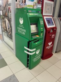 На самом деле банкомат ремонта ожидает ... Ригель замка выдвинут - рискну предположить что инкассаторы накосяпорили при смене кода замка сейфа, и замок теперь на замену. Обычная история :)
А скотчем приклеили чтобы открытая дверь и декоративная крышка по ногам людям не фигарила. Всё просто.