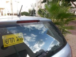 В Израиле такая, и точно такой же штамп в правах. Два года катаешься так, потом по почте присылают новые права, без штампа. Если в правах штамп есть - обязан повесить наклейку и на машину. Если в правах штампа нет - наклейку вешать запрещено. Если водителей двое, один начинающий, второй опытный, то наклейка будет на присосках, чтоб оперативно вешать и снимать. 
Вот собственно на фотографии такая.