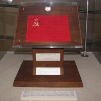 Данный кусок, оказался у премьер министра Нидерландов когда  в 1969 году гостил в США.  Ему подарили камень и он решил, что этот камень с Луны (только состоялся полет Apollo 11). О данном "факте" он всем говорил и ему все верили, как никак премьер министр. После его смерти, камушек продолжал  хранится у него дома (тоже занятный факт, ведь в частные коллекции грунт не передавали), а затем был передан в музей. 
Кусочки реголита, был официально переданы Нидерландам. Именно стране, а не премьер министру. И к тому кусочку дерева не имеет отношения.

P.S. Что Вы видите на фотографии ?
Это ведь грунт и его наличие является фактом. 
У Нидерландов аналогичный официальный стенд, но только с их флагом.