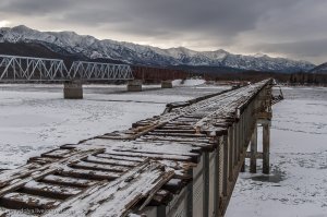 Да всё проще гораздо. Это и есть старый временный ж/д мост, никаких автомобилей там в помине быть не должно. И никто там ничего достраивать не будет, всё уже построено. Просто водилы так срезают расстояние. Капитальный ж/д мост находится по соседству.
