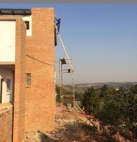 Точно не упадет:
там внизу палкой подпёрто и вверху двумя веревками привязано.