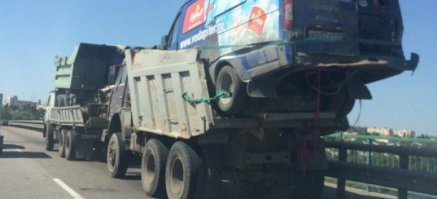 что КамАЗ везет на прицепе другой КамАЗ, тянущий, в свою очередь, еще один КамАЗ, в прицепе которого находится ГАЗель с автомобилем "Ока" внутри.