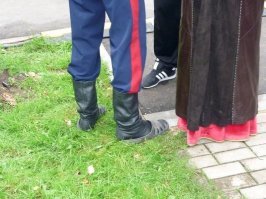 Эти никакие не модники. Скорее всего, танцевальный коллектив в "народном" стиле. Видимо, в сценической танцевальной обуви не разрешают на улицу выходить, вот парень и нашёл выход - готов на сцену выйти по первому зову (переобуваться не надо) и на улице можно пройтись  А у девушки верхняя одежда явно поверх русского сарафана одета :)