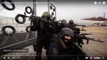 А давайте посмотрим, что здесь пытались сравнить!
1.1. Спецназ. 
В тяжелых брониках, касках, противоосколочных очках, но чаще - с открытыми глазами, в наколенниках и иногда - налокотниках, которые при скольжении по поверхности сползают.
Вооружение: автоматы Калашникова, в том числе с подствольными гранатометами (в случае необходимости), пистолеты, свето-шумовые и боевые гранаты. В составе группы могут быть пулеметчики, снайперы. 
Оружие точное, количество патронов в магазине небольшое, при выстреле происходит отдача. 
Дополнительный боезапас носится спереди, заряжание производится с нижней части оружия.
Оружие стреляет точно на достаточно больших для пейнтбола дистанциях, как правило работа ведется точными одиночными выстрелами или короткими очередями. Небольшой кустарник не является помехой для поражения.
В случае поражения противником, боец получает реальные травмы или погибает, соответственно, тактика боя строится в том числе исходя из этого.
1.2. Профессиональный спортивный пейнтбол
У каждого личный пристрелянный автоматический маркер, стреляющий очередями при нажатии на мягкий спуск, с кевларовым балоном, электронным фидером, автоматически с большой скоростью подающим шары, с крышкой, позволяющей засыпать шары, не открывая фидер, харнес с тубами, носимый за спиной, личная маска, с хорошими стеклами, пейнтбольная форма с усиленной защитой ног, паха, локтей, что позволяет делать подкаты с разбега.
Точность маркеров относительно небольшая, так как шары не идеально сбалансированы, на больших дальностях необходимо делать поправки, шары разлетаются при попадании в кустарник, не всегда пролетая насквозь.
Вместимость фидера около 200 шаров, засыпание шаров производится сверху маркера. 
Оружие нелетальное.
Всё это позволяет вести работу большими очередями, не бояться делать "прорывы", так как пораженный боец не получает никаких травм (только если сам неудачно упадёт).

2. С чем вышли на поле.
2.1.Спецназ
Дешевые прокатные маркеры, делающие один выстрел при одном нажатии на тугой спусковой крючок, с дешевыми фидерами, подающими шары за счет их собственного веса, из-за чего бывают холостые выстрелы при высокой интенсивности стрельбы, пологом наклоне маркера или когда три шара упираются друг в друга, перекрыв"воронку", с алюминиевым балоном. 
Шары размещены в прокатных харнессах с размещением туб за спиной. Засыпание производится сверху после открывания крышки фидера, после чего её нужно закрыть.
Маски тоже дешевые прокатные, запотевающие после легкой пробежки. Форма обычная с привычными для спецназа наколенниками.
Прокатные стволы маркеров могут быть грязные, царапанные, т.е. точность стрельбы тоже под сомнением.
2.2. Пейнтболисты
Всё своё.

Когда я это увидел, то просто пролистал в конец ролика, чтобы убедиться в правоте своих предположений о результате встречи.
Считаю, что более честным было бы провести встречу пейнтболистов и спецназа с использованием ОДИНАКОВОГО страйкбольного снаряжения или хотя бы дешевого прокатного пейнтбольного.
ПС. Автомат в руках держал, маркер тоже.