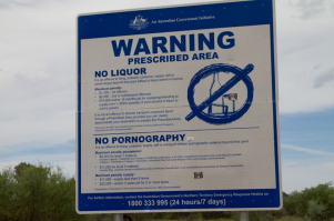 Здесь, скорее всего, знак стоит на въезде в резервацию австралийским аборигенам. У этих ребят реально проблемы с алкоголем. Таким образом, правительство Австралии старается бороться с алкоголизмом аборигенов. 
Про продажу аборигенам порнопродукции тоже есть запрет, но сейчас уже не помню чем он продиктован. Возможно тем, что эти дети природы приступали к самоудовлетворению сразу же и там же где им попал в руки чудесный журнальчик.