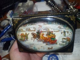 моя мать всю жизнь там работает. знаю всю их тусовку со своего рождения.. тамошний состав художников делится на авторов и копировальщиков. первые делают новые композиции, долго и нудно доказывая комиссиям, что собака должна бежать за санями, а баба в санях не должна на нее смотреть, и сто раз переделывая композиции, пока комиссия не примет ее. вторые весь день херачат десятками в сутки копии. первым платят больше, но реже, вторым мало, но поштучно. моя мать из группы авторов, вероятно, из-за моего рождения стала работать дома. все детство вонь лаков и красок до тошноты и головных болей. дома большое количество "забракованных" коробок, брошек и тд. никто ни в жизни не заметит, что что-то в них не так, тк это не так есть дед должен стоять на метр левее или ветка березы должна быть ниже по сказке и тд.. все предметы обязательно содержат золото. конечная стоимость на самом деле, можно сказать, не ограничена, обычно ограничивается, собственно, заказом. в конце 80х и в 90х зарплату на фабрике просто перестали платить. сначала выдавали японскими телевизорами и видаками, кстати, очень высокого качества. а потом и вообще все стухло. но как только открыли границы, и сюда ломанулись бохатые иностранцы, те готовы были платить любые деньги за такие вещи, тк в их прогнивших капитализмах таких школ просто не было) наши люди тут же сообразили это дело, из тех же фабричных стали образовываться минимальные коллективы, способные производить такие вещи в домашних условиях с нуля, и стали сами организовывать их сбыт. почему этим не занималась сама фабрика - понятия не имею. в итоге на фабрику работали все по минимуму, сколько требует трудовой договор, а на кустарные производства уходило в десятки раз больше сил. и выпуск был соответствующий. ну и деньги само собой получалось зарабатывать. хотя, здоровья, конечно, надолго так не хватило.. недавно ее (матери) работы выставлялись в музее. причем вся выставка целиком была только ее. на отдыхе (на рыбалке или еще где) она обычно берет лист чуть ли ни туалетной бумаги, дебильную детскую гуаш или акварель, ищет и прилаживает к земле табуретку минут 20, после чего за 1 минуту выдает шедевр. пыталась меня в детстве на это дело подсадить, но у меня вместо 1 минуты как раз через 20 минут все краски становились одинакового цвета говна. как и лист бумаги, какими бы качественными изначально они все ни были. поэтому я стал главным инженером)