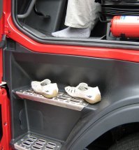 Чушь полная...
Табличка с именем просто для прикола. На дальняке с 1992 года, одно время стояла табличка "D" в кружке из звездочек и "Alex". Но это не значит, что за рулем был Алекс из Дойчланда (из Германии), да и номера всегда были подмосковные. Просто табличка красивая... Более того, когда из кабины перебрался в кабинет и начал в числе прочего заниматься дополнительным обучением и стажировкой водителей, добился, чтобы на ветровых стеклах грузовиков компании вообще ничего не было: это все отвлекает и ограничивает обзор.
Если говорить о радиосвязи, то вызов в канале встречного идет по марке грузовика. Можно уточнить: "на таком-то километре" или привязаться к неком объекту на дороге - населенный пункт, мост, развилка и прочее. Попутного - только по номеру (чаще прицепа) и опять привязка к местности. Дело в том, что табличку с именем не видно при встречном разъезде, а тем более при попутном движении...
Табличка "пустой" (вариант "пустой - трезвый - без денег") наследие славных 90-х. Бытовало мнение, что в этом случае гайцы не остановят, а пацаны на трассе не заинтересуются... Естественно на предмет вымогательства: мол, взять с меня нечего - не тратьте время. Но никогда такая табличка не помогала. Более того, в 90-е иногда с водителем расплачивались налом за доставку груза. Или он расплачивался за груз налом при получении. В этом случае "пустой" это значит "уже разгрузился" = деньги могут быть на кармане, "еду на погрузку" = тоже самое... Народу, правда, нравится, но это лишь для самоуспокоения при недостатке опыта...
Табличка с названием города тоже по приколу (не более). Попутный груз ищут не по табличке, а в канале (в переговорах по рации) есть информация. По опыту если под ветровым стеклом стоит, например, "Архангельск", то на стоянке максимум подойдут люди южной национальности, попутный предложат, но вероятность, что кинут равна 100,1 процента. Предложение в канале, тем более таких диспетчеров по трассе обычно знают, обычно предполагает минимальный риск. Даже потому, что слушает вся трасса и при случае предупредить собрата - право и обязанность любого нормального водителя...
p.s. Автор, раз уж начал писать о дальнобойщиках, поясни в чем прикол. Предварительно уточню: эта тема для ЕС, в основном - Германии. Однако эта глупость позволяет избежать штрафа до 2000 евро...