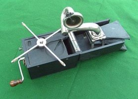 Вы не поверите, но я не только видел их вживую, но и пользовался по назначению. Без резонатора звук не громче мышиного писка.

Вот родной брат механизма из поста: складной портативный патефон. И у него есть рупор-резонатор, тоже складной.

Где аналогичный узел у механизма из поста?
Учитывая, что выход трубки тонарма упирается в поверхность стола, напрашивается простой вывод: должна была быть вторая половина шкатулки, которая надевается снизу и содержит рупор. Иначе эта механика просто не работает.