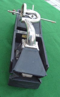 Вы не поверите, но я не только видел их вживую, но и пользовался по назначению. Без резонатора звук не громче мышиного писка.

Вот родной брат механизма из поста: складной портативный патефон. И у него есть рупор-резонатор, тоже складной.

Где аналогичный узел у механизма из поста?
Учитывая, что выход трубки тонарма упирается в поверхность стола, напрашивается простой вывод: должна была быть вторая половина шкатулки, которая надевается снизу и содержит рупор. Иначе эта механика просто не работает.