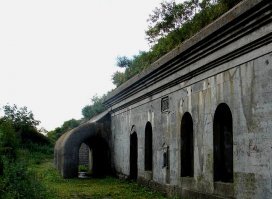Форт Поспелова на о.Русском, Приморский край
На вершине горы Поспелова, которая имеет высоту 150 метров, расположился знаменитый форт Поспелова или форт князя Дмитрия Донского. Это укрепление является южным рубежом знаменитой Владивостокской крепости. Автор комплекса - русский инженер П.А.Гнучев. Ранее, до 1903 года форт называли Временным укреплением №4, далее переименовали в современное название. Находится он на полуострове Саперный и считается памятником архитектуры, достопримечательностью мирового масштаба. Во времена Советского Союза форт Поспелова использовали в качества артиллерийских складов и боезапасов Школы Оружия КТОФ.
Это укрепление является образцом русской фортификации. В стенах форта можно увидеть вмурованные в амбразуру кофра 9ти фунтовые пушки и два пулемета, которые обстреливали напольные рвы, а из бетонного капонира – горжевые, служившим мостиком через рвы, при этом обеспечивая солдатам максимальное перемещение в разные точки форта Поспелова. Подземный коридор снабжен световыми люками, при этом потерна соединена с кофрой внутренним двориком. Выход же из потерны служил укрытием для тяжелых выкатных пушек. На сегодняшний день световые люки закрыты крышками. В бетонном массиве казармы подразумевалось постоянное проживание солдат. Фасад форта отделан массивными карнизами, на котором имеется священная икона.