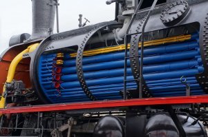 Котел не "трубчатый", а огнетрубный. Переводите правильно. Кстати, все медное, трубы просто вставлены в стенки котла и завальцованы. И такое давление держат, на столько все точно и тщательно сделано.

Иду как-то мимо депо, смотрю, паровоз стоит. Паровоз, как новый и вокруг никого. Не удержался, забрался в будку. Стою, все рассматриваю, но руками не трогаю. Увлекся, не заметил, как железнодорожник подкрался. Говорит, зачем это ты, гад паровоз ломаешь? А я ему, неужели ты думаешь, что я паровоз обидеть могу? Я паровозы только в кино видел, и то из далека. А тут настоящий целый паровоз, и близко. Ну не мог я мимо пройти. Железнодорожник проникся, и долго мне про паровозы рассказывал, даже разрешил регулятором подрегулировать и педальку нажать, чтоб топка открылась. Вот там я про котел все и узнал. А паровоз этот оказался знаменитостью. Он действительно рабочий, целый, на угле. А работал этот паровоз кинозвездой, и во многих фильмах снимался. Надеюсь, что и сейчас жив, здоров.