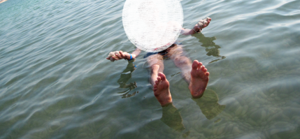 Водой из Мёртвого моря запрещено умываться, а глоток Мёртвого моря может быть смертельна. В воде находится не более 15 минут и потом обязательно покупаться в пресной воде.
Что поразило так в воде соль гранулируется и чем глубже, тем больше шарики из соли. (На фото в руках соль со дна)
Ещё из прикольного, если лежишь в воде, естественно на спине, опустить прямые ноги на дно не реально, для этого надо поджать ноги, потом перевернуться вертикально и потом встать на ноги. 
По поводу поводу того что опасно переворачиваться на живот - бред, просто переворачивайтесь на бок. (Опять же, смотрите фото)
И ни слова про глубину залегания, проблемы Мёртвого моря и регулярные полёты истребителей над головой. 

Но Мёртвое море не одиноко, если у вас нет денег на Израиль, а он не дешевый. В Геническе на Арабатской стрелке есть Солёные озёра, тоже можно читать в воде и не утонешь, тоже есть лечебные грязи и намного дешевле.