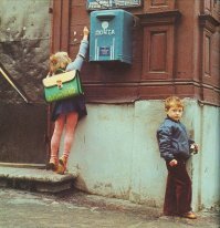 Закладку прячет, парень на шухере.
И не надо про письмо писать - она явно за ящик лезет, а не в него.