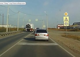 Кусок увеличенного и зашарпленного кадра.
Видно сплошную осевую. 
Со стороны регистратора один знак главной дороги.
Со стороны фуры такого знака нет.