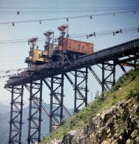 В детстве жил в 1 км от строящейся Ингурской ГЭС в ГССР. Там было всё: и канатная дорога, и вертолёты, и "кабель-краны".
Канатка была обычная с небольшими вагонетками, непрерывным потоком гнала щебень из долины, километра за 4. Впрочем, в моей сознательном возрасте работала уже лишь эпизодически, а скоро и вовсе стала лишь источником подшипников для наших самокатов.
Вертолёты, Ми-8, таскали всякие ажурные металлические конструкции, типа тех же электро-опор. Конструкции по объёму были сильно больше самих вертолётов, но по массе не такие уж и тяжелые. Иногда падали. Конструкции. Раз и вертолёт упал.
Самые прикольные были "кабель-краны". Гигантские хреновины ближе к хребтам гор с обоих сторон плотины, между ними натянуты тросы, по которым двигались каретки, от которых в свою очередь тросы вниз. Вот они могли любой груз в любую точку тела платины доставить. На фотке их три, но вроде вначале было побольше, штук 5-6. Как их там на горе собирали - я хз. Жаль, не найду сейчас фото, где видно их конструкцию в целом.
Ну и все горы на подходе к платины были просто окутаны сетью дорог на разных высотах, массу всего везли просто грузовиками.
И всё это в 70х годах прошлого века.