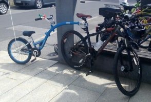 Обычный тандем детский велосипед. Есть нескольких типов. Это чисто нависной, он не может сам ехать. Есть такой же, только с передним колесом (у детского велосипеда), его можно отстегнуть и ребенок поедет сам. Еще есть похожий тандем, заканчивается платформой, куда ставиться обычный детский велик любой марки и едет. Смысл всего этого в том, что ребенок не всегда может проехать много, или через интенсивное движение, так его можно оттащить в парк и там пусть сам катается. Я хотел в свое время такой купить, но жаба задушила. Стоит около 100-150 евро.