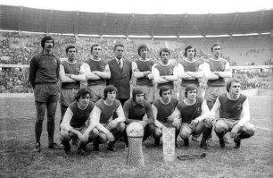 Про джинсы. Они изнашивались, и люди покупали новые. Старые использовали для черной работы. Или на них молиться надо было до полного истлевания? 
Про рубашки. В 70-х в моде были приталенные рубашки и расклешённые брюки. Таков был модный силуэт. Покупные рубашки молодёжь вручную приталивала (зашивали вытачки), в развесистых рубахах мало кто ходил.
Причёски. При чём тут комсомольцы и бригады комтруда? Комсомольцами тогда были 99% молодёжи, что не мешало им модно одеваться и стричься. И речь идёт не о патлатых, а просто об удлинённой мужской стрижке, закрывающей часть уха (даже мужчины в возрасте многие так стриглись, ходить с голыми ушами было как бы неприлично). Вот студенты, строители БАМа и спортсмены 70-х: