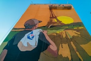 у нас в Украине, был флешмоб, взять в экзотическую страну фирменный пакет очень популярной сети супермаркетов АТБ, и зафотаться с этим пакетом на плече на фоне каких-нибудь достопримечательностей далекой страны. Ну типа не реклама , а показать что обычные люди среднего класса ездят по заграницам и ради некоторой экономии берут пакеты из супермаркета под домом на Родине.( это типа в России сеть "Магнит" или"Пятерочка").
Так вот в Днепропетровске, изобразили один популярный снимок из интернета парня с пакетом АТБ на плече, на фоне Эйфелевой башни. По иронии судьбы, стена дома на которой изображение, прямо напротив в 15-ти метрах от входа в супермаркет сети конкурентов ))