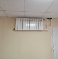 Судя по всему - это батарея в коридоре. То, что она под потолком - требование пожарной безопасности. Радиаторы расположенные на путях эвакуации должны располагаться так чтобы о них в условиях задымления не бились люди.