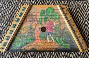 Это цимбала(цимбалы). А еще точнее, игрушка времен СССР. Под струны клались своего рода ноты, соответствующие струне, что позволяло играть, совершенно не зная ни нот, ни струн.