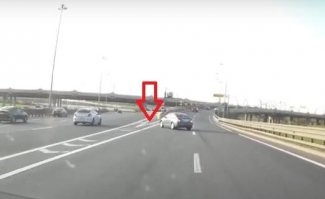 Что за олень?? Зачем он попёрся задом через все ряды? Достаточно было доехать до островка, встать там, пропустить всех и спокойно уехать направо. Хотя, конечно, движение задом там запрещено, но "все так делают".