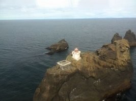 АФтАру в помощь)))
Маяк расположен на самой высокой из трех близлежащих скал. С определенного ракурса кажется, что эта скала под названием Háidrangur острая, но на самом деле она довольно плоская и широкая. И единственный способ попасть туда   это вертолет. Одно из главных условий, необходимых для полета на остров,   ясная, безоблачная погода. А для Исландии это нечастое явление.
Раньше на этом труднодоступном острове-скале жили смотрители, которые занимались техническим обслуживанием маяка и поочередно сменяли друг друга. Много десятилетий подряд работники добирались сюда на лодке, чтобы потом взобраться на опасную высоту по трудному подъему среди скал.
Сегодня маяк полностью автоматический. Иногда сюда прилетают рабочие проверить состояние маяка, подправить возможные неполадки. И виды отсюда просто невероятные.
Это необычное место вдохновило исландскую королеву саспенса, писательницу Ирсу Сигурдардоттир на создание детектива-бестселлера «Why Did You Lie?». Еще у маяка есть своя страничка в фейсбуке, хотя можно предположить, что интернет на труднодоступном утесе оставляет желать лучшего.