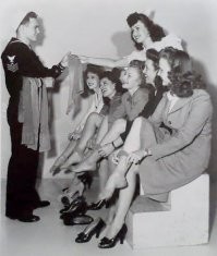 "Моряк привез из плаванья дефицитные чулки, 1940-е".
Всё наоборот. Это агитационное фото - «Девушки сдают чулки на нужды ВМФ США».
В начале войны был дефицит нейлона, правительство США обратилось с просьбой жертвовать чулки для армии.