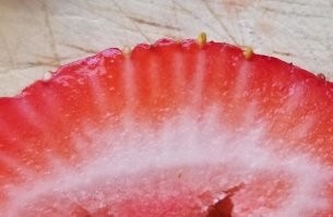 Начнем с того, что это не клубника, а земляника садовая она же "Виктория". 
Во-вторых, земляника это не ягода а орех, и те самые семечки это и есть настоящие плоды - орехи,  с жесткой скорлупой и ядрышком внутри. 
В-третьих, сладкая мякотка -  это разросшиеся и сросшиеся плодоножки  которые как им и положено идут каждая к своему ореху. 

Живите с этим!