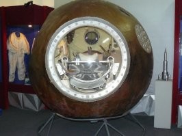 Один вон у меня (вернее на квартире у родителей в селе) даже с балкона видно , без всяких шуток, но это уже более современный, где то в начале 2000-х побывал в космосе, его я "не простукивал" , но на вид такой же, насчет материала, как и другой, 60-х, который внутри музея. Вот его я обследовал, со всех сторон. 
Там точно не асбест, что то типа пенобетона на звук постукивания . Но если сорвет защиту, то любой металл там вряд ли выдержит более чем несколько секунд. Иллюминатор там совсем маленький, с ладонь (ну, две ладони рядом по площади), так расположен, что он во-первых, со стороны парашюта, т.е. тыльной, а во-вторых, он хоть и закреплен в раме из металла, с уплотнителями наверняка, но снаружи заглублен и закрыт по бокам. 
Первый - космонавта 3, второй - который с балкона видно, на улице во дворе... даже и не знаю точно кто слетал, надо сходить табличку почитать