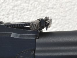 "Сравните расстояние между стволом и мушкой и размер гильзы."  
1. Целится надо было выше гильзы на пару сантиметров, в бечевку. (это при условии вертикально висящей гильзы, если гильза с наклоном- надо вообще целиться просто над ней)
2. На прицеле П, ствол автомата не параллелен земле. Т.е. надо учитывать возвышение ствола.
3. 10 шагов  это 7-8 метров.
4. Поймать и вычислить 2 см в прицеле автомата на расстоянии 8 метров?
5. Солдат знал высоту мушки АКМ в миллиметрах?

Слишком много факторов....