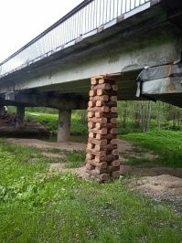 Реально идиотская конструкция. По одной опоре в середине!
Любое усилие с одной стороны если больше, то по закону рычага огромное "сваливающее" в бок усилие на точку крепления опоры к балке. 
Возможно шутка, но даже простые деревянные стойки по бокам значительно разгрузят узлы.